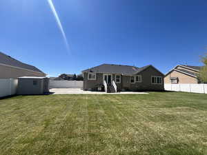Back of house with a storage shed, an outbuilding, a fenced backyard, entry steps, and a patio