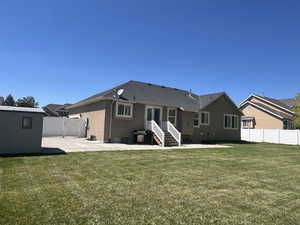 Rear view of property with a gate, a lawn, fence, a patio, and stucco siding