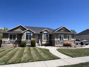 Craftsman inspired home featuring stone siding, a front lawn, and stucco siding