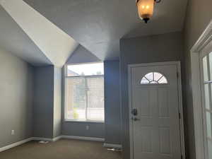 Entryway featuring new carpet, a vaulted ceiling, and a wealth of natural light
