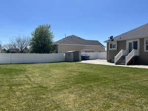 View of yard with a patio area, a fenced backyard, an outbuilding, and a storage shed
