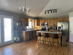 Kitchen with light wood finished floors, light countertops, rail lighting, and appliances with stainless steel finishes