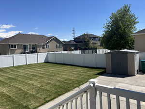 View of yard with a storage unit, a residential view, an outbuilding, a fenced backyard, and a patio area
