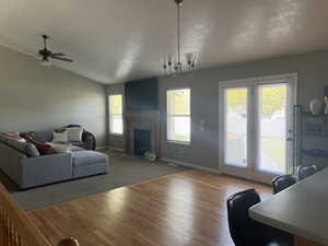 Living area with a fireplace with flush hearth, baseboards, lofted ceiling, and wood finished floors
