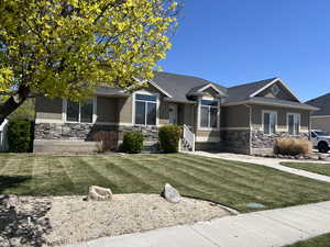 Craftsman-style home with stucco siding, a front lawn, and stone siding
