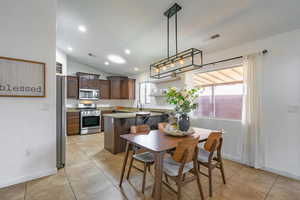 Dining area featuring lofted ceiling, visible vents, and light tile patterned floors
