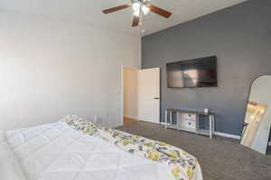Carpeted bedroom featuring vaulted ceiling, a ceiling fan, and baseboards