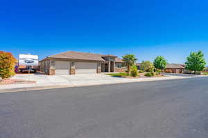 Ranch-style home featuring a tile roof, stone siding, concrete driveway, a garage, and stucco siding