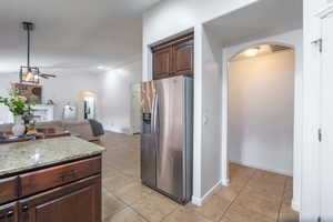 Kitchen featuring arched walkways, ceiling fan, stainless steel refrigerator with ice dispenser, and light tile patterned floors