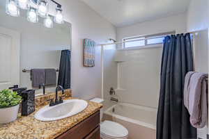 Full bath with toilet, vanity, and shower / bathtub combination with curtain