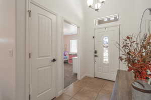Foyer featuring a chandelier, baseboards, light colored carpet, and light tile patterned floors