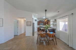 Dining area featuring baseboards, lofted ceiling, and light tile patterned floors