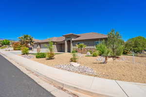 View of front facade with a tiled roof, stucco siding, an attached garage, driveway, and stone siding