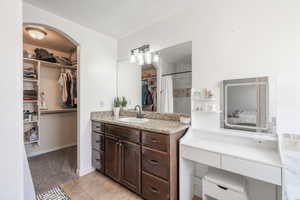 Bathroom featuring tile patterned floors, vanity, and a walk in closet