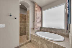 Full bathroom featuring a garden tub and tiled shower