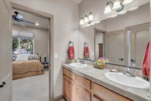 Ensuite bathroom with ceiling fan, a sink, connected bathroom, and double vanity