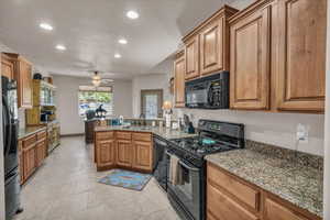 Kitchen featuring a peninsula, a sink, recessed lighting, a ceiling fan, and black appliances