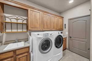 Laundry room featuring separate washer and dryer, cabinet space, a sink, and recessed lighting