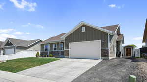Craftsman-style home with a front lawn, stone siding, fence, a garage, and board and batten siding
