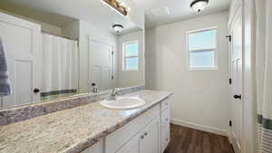 Full bathroom featuring baseboards, vanity, and wood finished floors