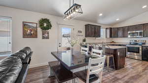 Dining area with baseboards, lofted ceiling, dark wood-style flooring, and recessed lighting