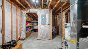 Unfinished below grade area featuring electric panel and heating unit