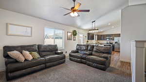 Living room with ceiling fan, baseboards, lofted ceiling, and dark colored carpet