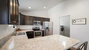 Kitchen featuring stainless steel appliances, light countertops, a sink, washer / dryer, and dark brown cabinetry