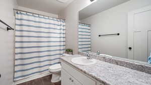 Bathroom featuring curtained shower, wood finished floors, toilet, vanity, and a textured ceiling