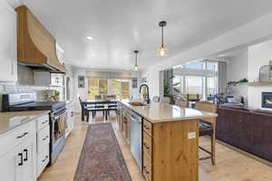 Kitchen featuring a breakfast bar, a sink, a glass covered fireplace, appliances with stainless steel finishes, and open floor plan