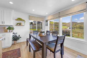 Dining area with light wood-type flooring, baseboards, and a healthy amount of sunlight