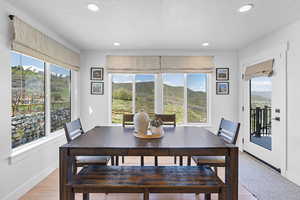 Dining space with baseboards, a mountain view, light wood-type flooring, and recessed lighting