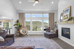 Living room featuring ceiling fan, recessed lighting, a glass covered fireplace, and carpet