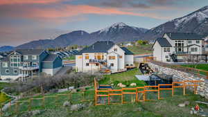 Back of property at dusk with a residential view, a fenced backyard, stairway, and a mountain view
