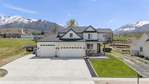 Craftsman-style house with concrete driveway, a front lawn, a mountain view, fence, and a garage