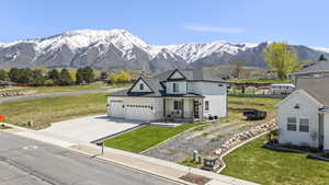 View of front of property featuring an attached garage, driveway, a mountain view, and a front yard