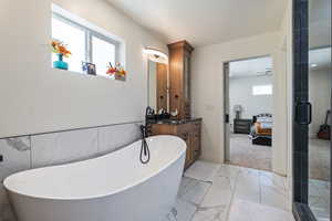 Bathroom with marble finish floor, connected bathroom, vanity, and a stall shower