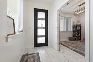 Foyer entrance featuring marble finish floor, an inviting chandelier, visible vents, and baseboards