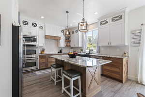 Kitchen with premium range hood, backsplash, stainless steel appliances, and light wood-style floors