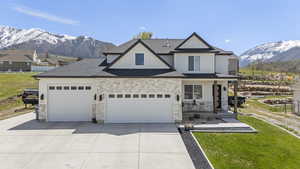 View of front facade with board and batten siding, driveway, a porch, a mountain view, and a garage