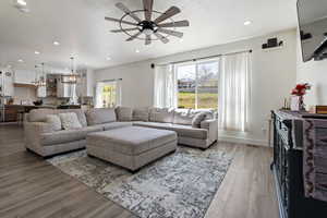 Living area featuring wood finished floors, a textured ceiling, ceiling fan with notable chandelier, baseboards, and recessed lighting