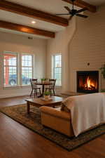 Living room with wood finished floors, beamed ceiling, a warm lit fireplace, recessed lighting, and a ceiling fan