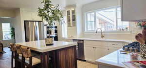 Kitchen with a sink, appliances with stainless steel finishes, white cabinets, and light countertops