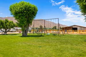 View of yard with playground community, an outbuilding, a mountain view, and an exterior structure