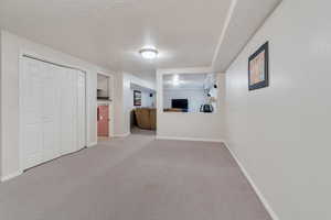 Interior space with a textured ceiling, carpet, and baseboards