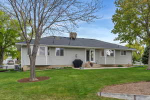 Rear view of house with a yard, entry steps, and central AC