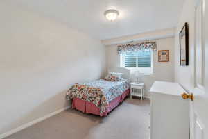 Bedroom with baseboards and light carpet