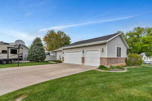 Exterior space with a lawn, concrete driveway, an attached garage, and brick siding
