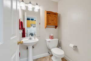 Bathroom with toilet, tile patterned floors, washer / dryer, and baseboards