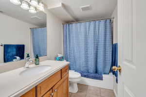 Full bath featuring vanity, tile patterned floors, toilet, visible vents, and a textured ceiling